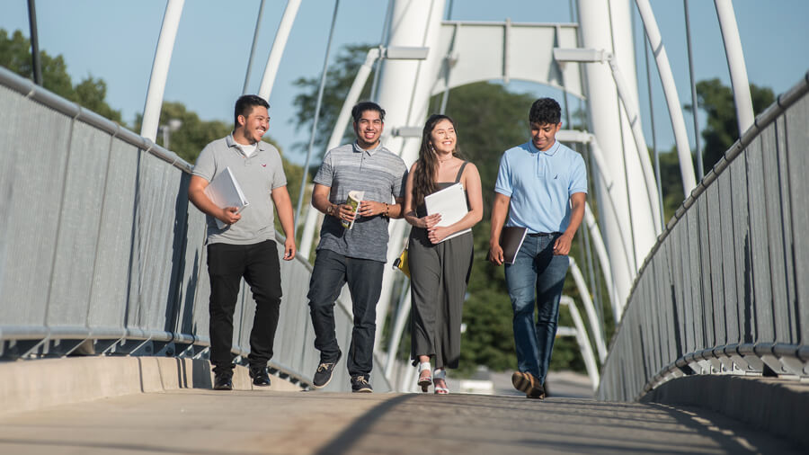 Four students walk across the Ron Venderly Family Bridge.