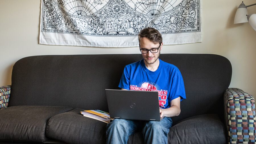 A student uses their laptop while sitting on their couch.